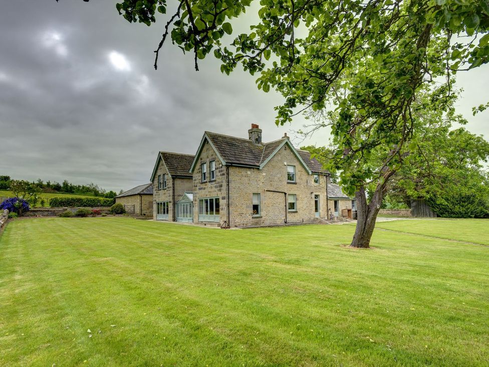 A house with a large lawn and trees at The Farm House in Aldbrough St. John near Barton