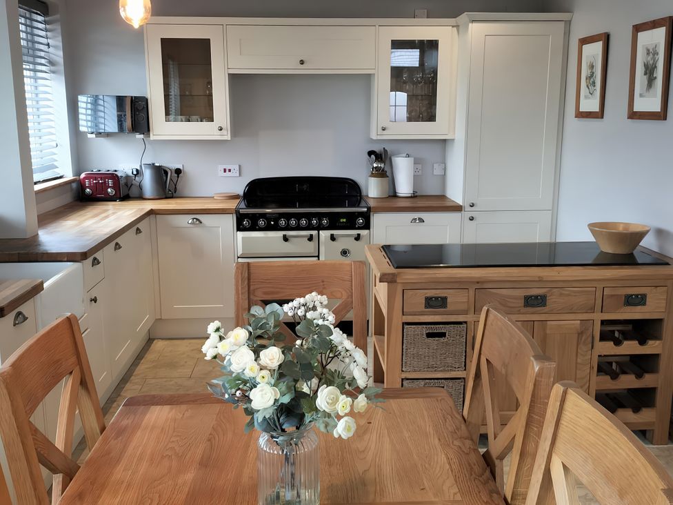 A kitchen with a stove, cabinets, and a table with chairs at 1 Maes Y Ffynnon in Menai Bridge