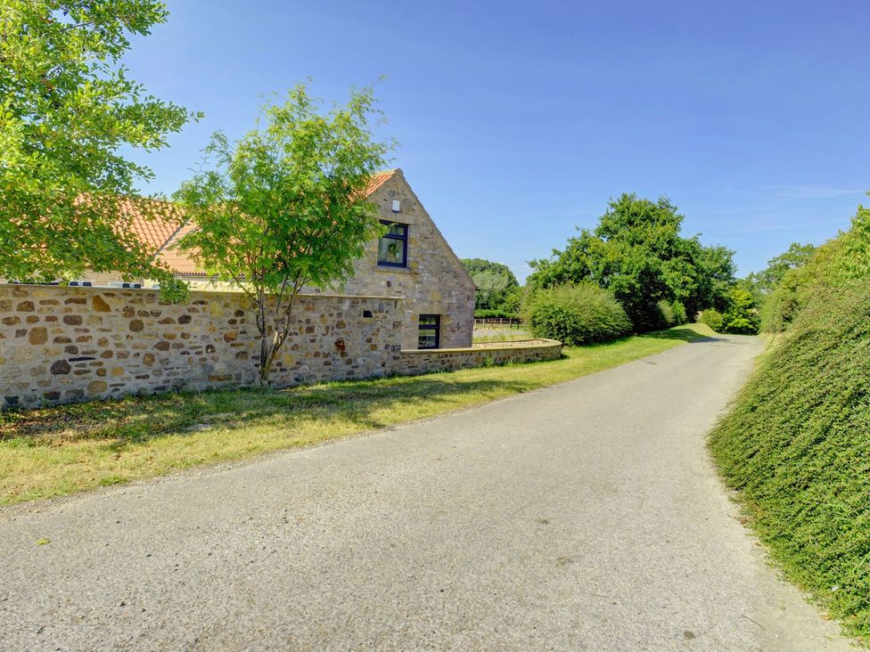 A house and tree alongside a road at The Gate House in Aldbrough St. John near Barton