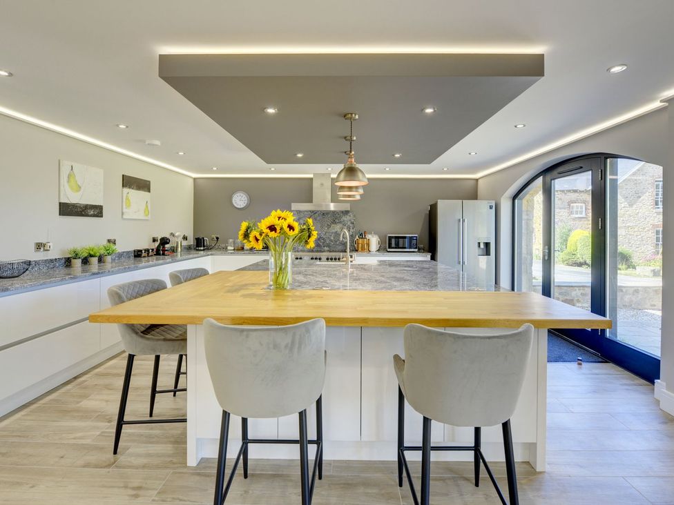 A kitchen with a central island and stools at The Gate House Aldbrough St. John near Barton