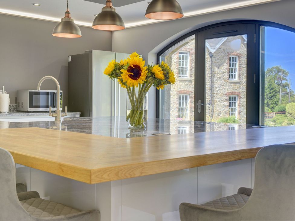 A kitchen with a large island and a vase of sunflowers at The Gate House in Aldbrough St. John near Barton