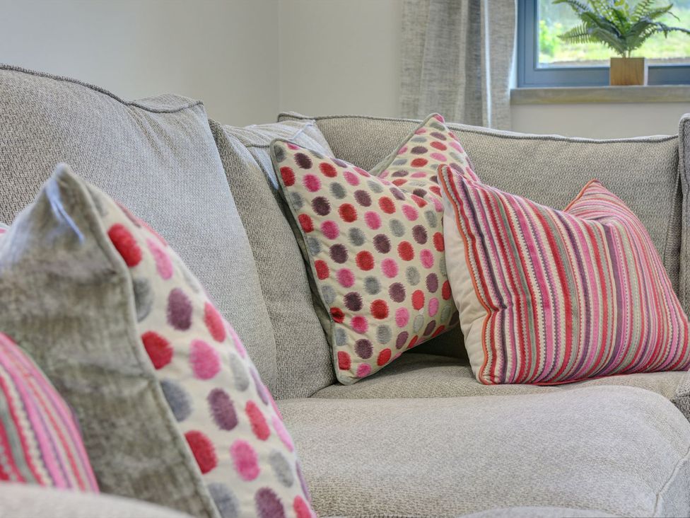 A sofa with patterned cushions and a plant next to a window at The Gate House in Aldbrough St. John near Barton