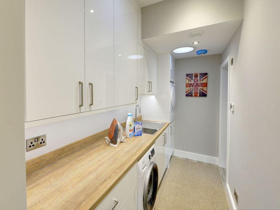 A laundry room with a washing machine, sink, and iron at The Gate House in Aldbrough St. John near Barton
