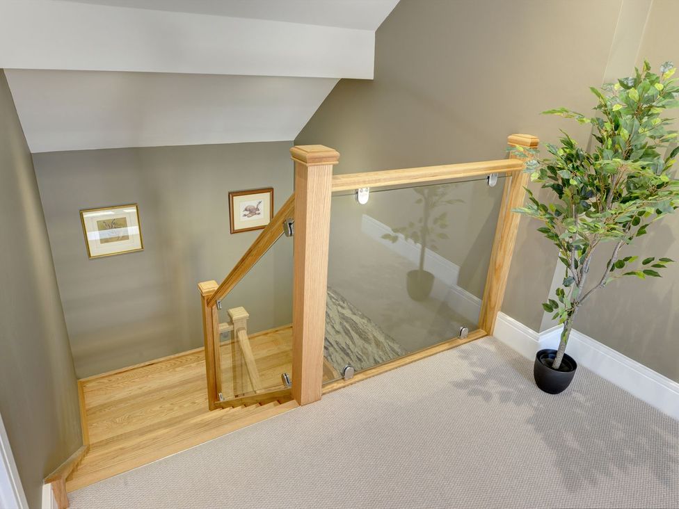 A staircase with wooden railing and decorative plant at The Gate House near Aldbrough St. John