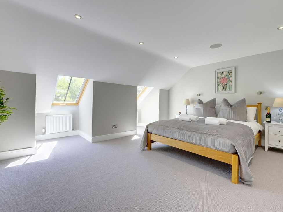 A bedroom with a bed and windows at The Gate House in Aldbrough St. John near Barton