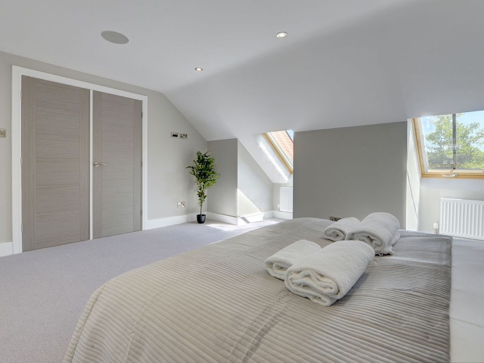 A bedroom with a bed and towels at The Gate House in Aldbrough St. John near Barton