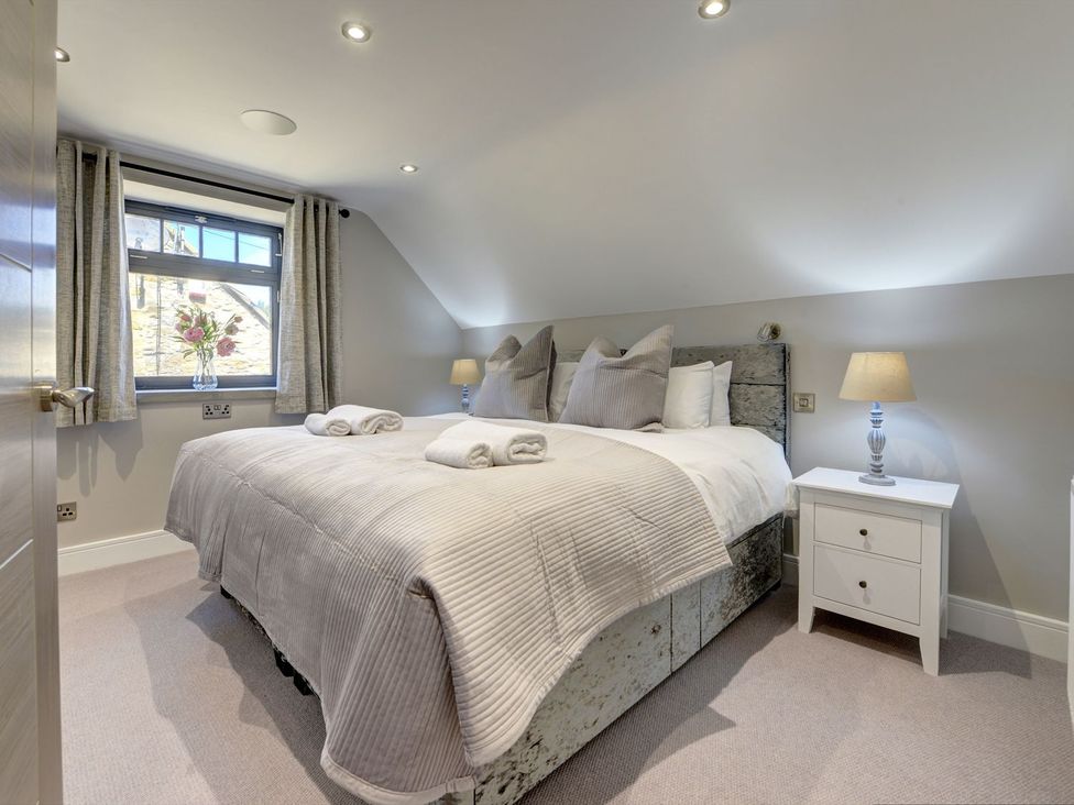 A bedroom with a double bed and windows at The Gate House near Aldbrough St. John