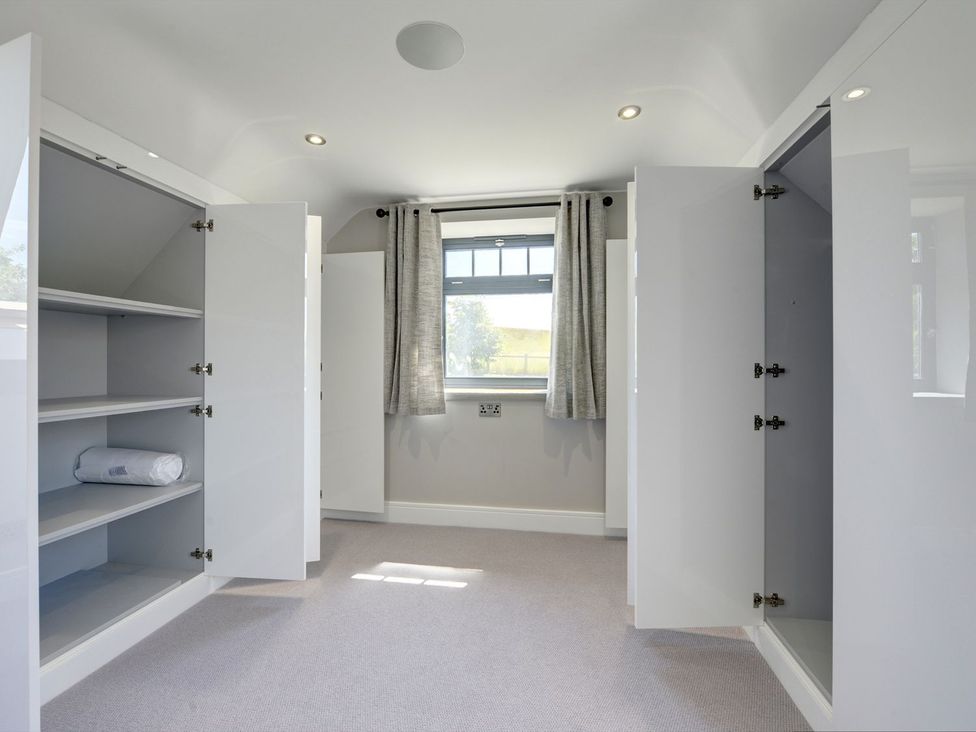 A bedroom with open wardrobes and shelves at The Gate House Aldbrough St. John near Barton