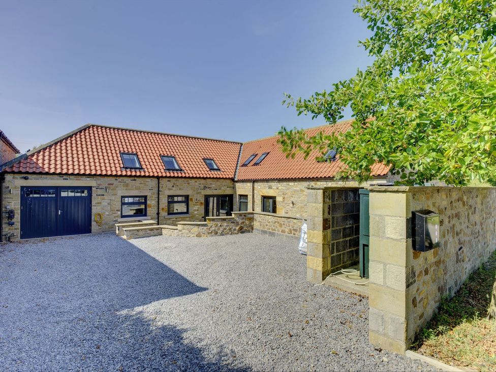 A house with a gravel driveway and trees at The Gate House in Aldbrough St. John near Barton