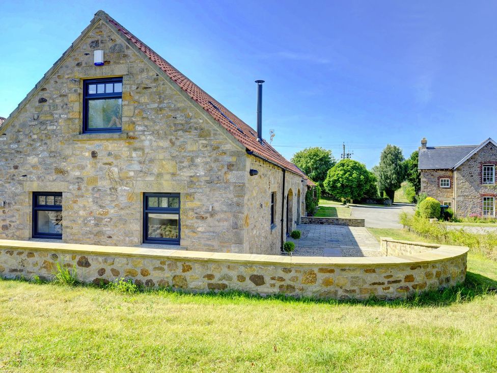 A stone house with windows and a garden at The Gate House in Aldbrough St. John near Barton