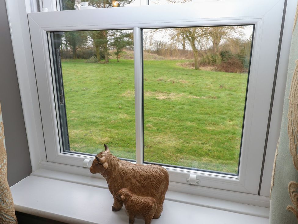 A window view with a decorative cow figurine at Hollymoor Hall Farm in Richmond