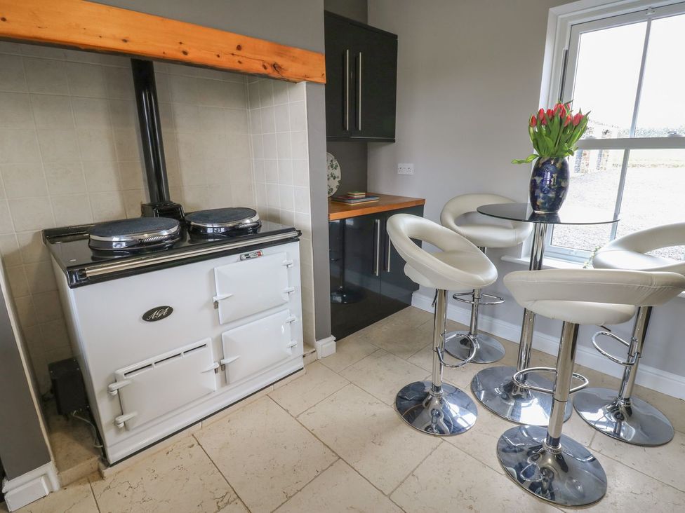 A kitchen with a cooktop and bar stools at Hollymoor Hall Farm in Richmond