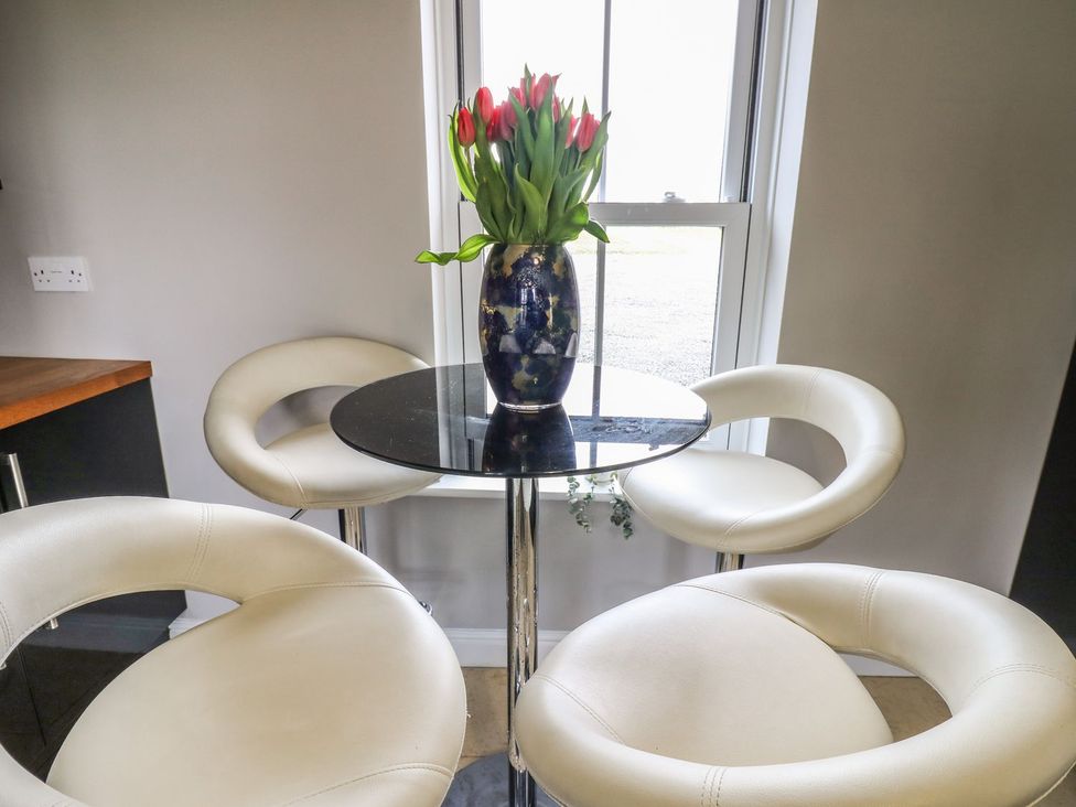 A dining area with a table and bar stools at Hollymoor Hall Farm in Richmond