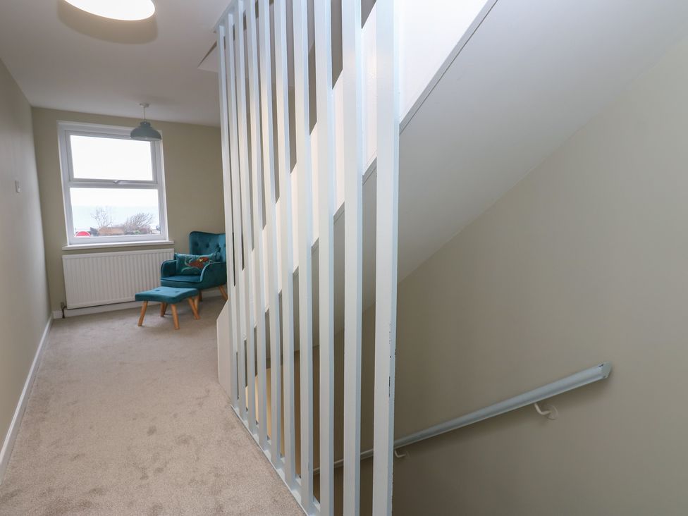 A hallway with a staircase and armchair at 11 North Terrace Seaham