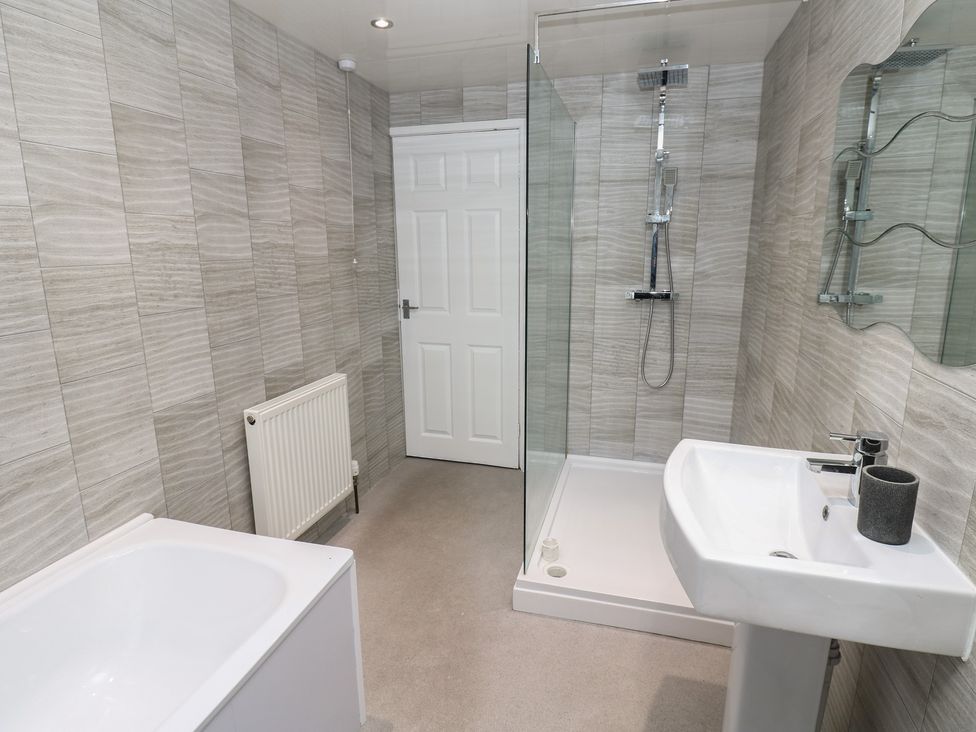 A bathroom with a bathtub, shower, sink, and radiator at 11 North Terrace in Seaham