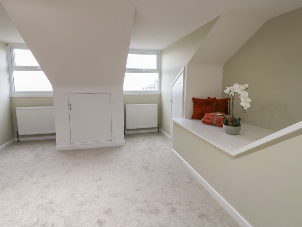 A room with windows and a shelf containing cushions and a plant at 11 North Terrace in Seaham