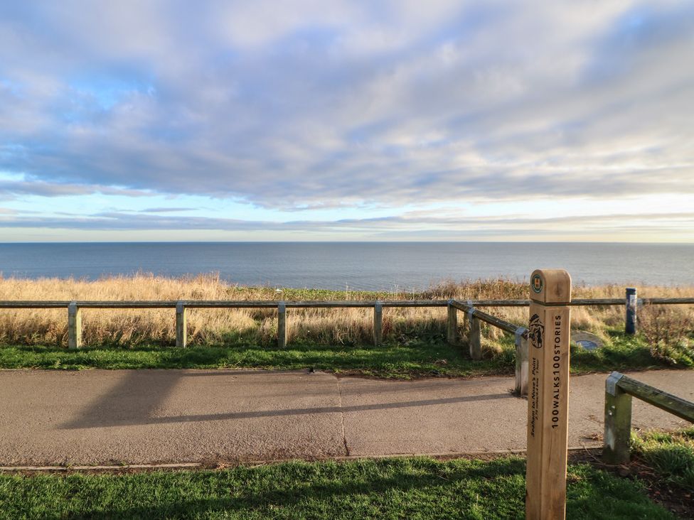 A view of the ocean with a sign by the path at 11 North Terrace in Seaham