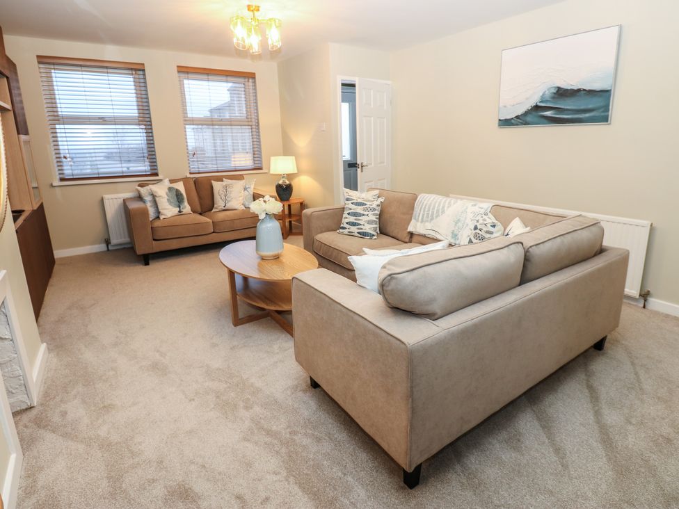 A living room with a sofa and armchair at Eleven Tides in Seaham