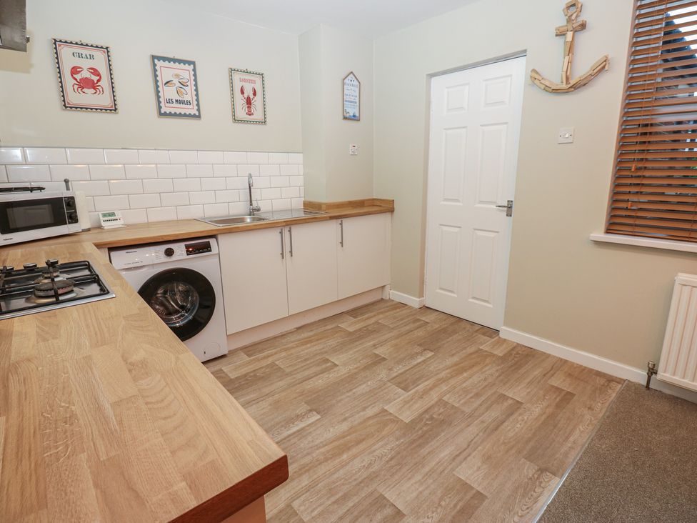 A kitchen area with appliances and wall art at Eleven Tides in Seaham