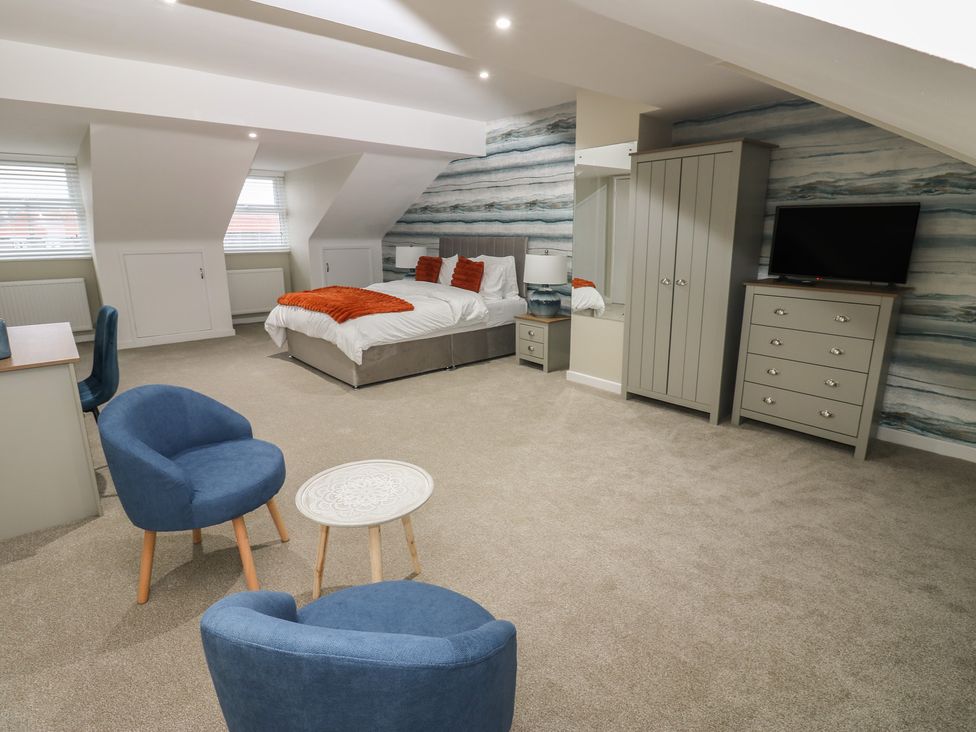 A bedroom with a bed, wardrobe, and armchairs at Eleven Tides in Seaham
