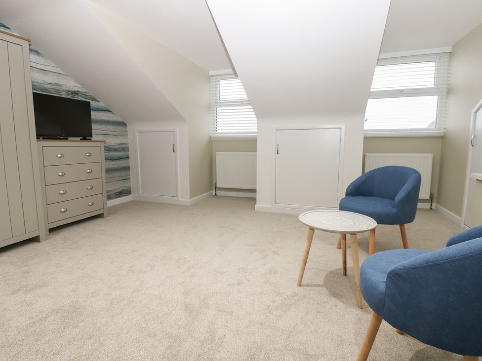 A bedroom with a television and blue chairs at Eleven Tides in Seaham