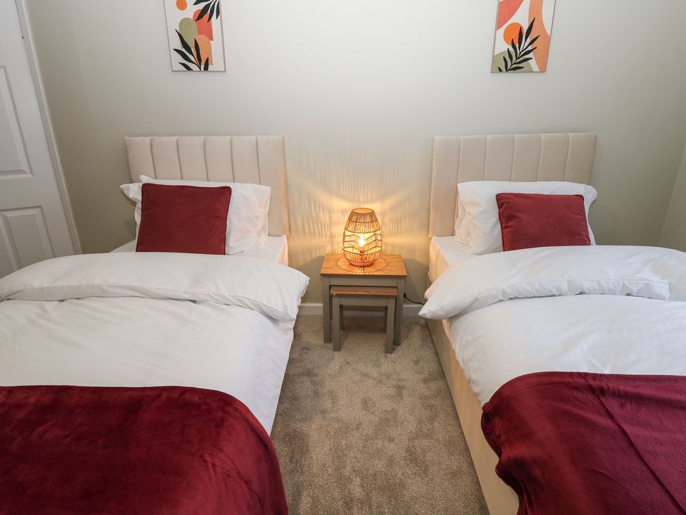 A bedroom with two single beds and a lamp on a side table at Eleven Tides in Seaham