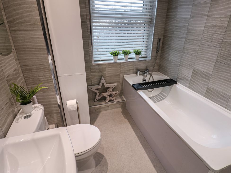 A bathroom with a bathtub, toilet, and sink at Eleven Tides in Seaham
