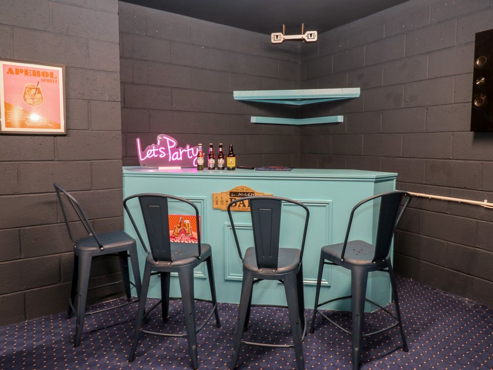 A home bar area with a neon sign and bar stools at Eleven Tides in Seaham