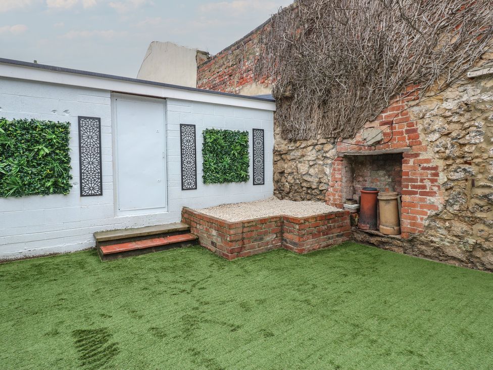 A garden with a door, steps, and a brick fireplace at Eleven Tides in Seaham