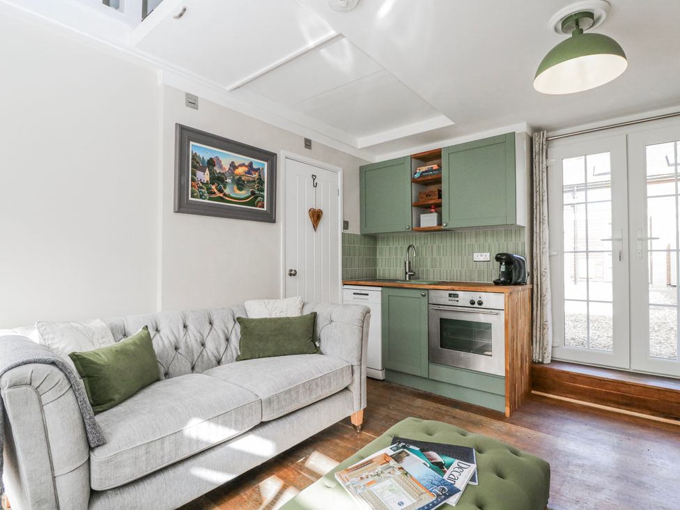 A living room with a sofa and kitchen area at Firefly Cottage