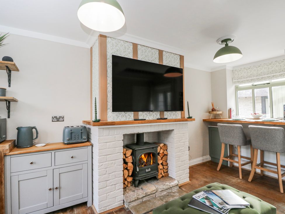 A living room with a fireplace and television at Firefly Cottage