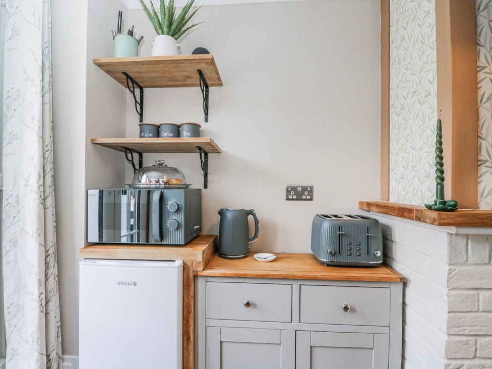 A kitchen area with appliances and storage at Firefly Cottage