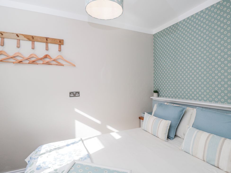 A bedroom with a bed and wall hangers at Firefly Cottage