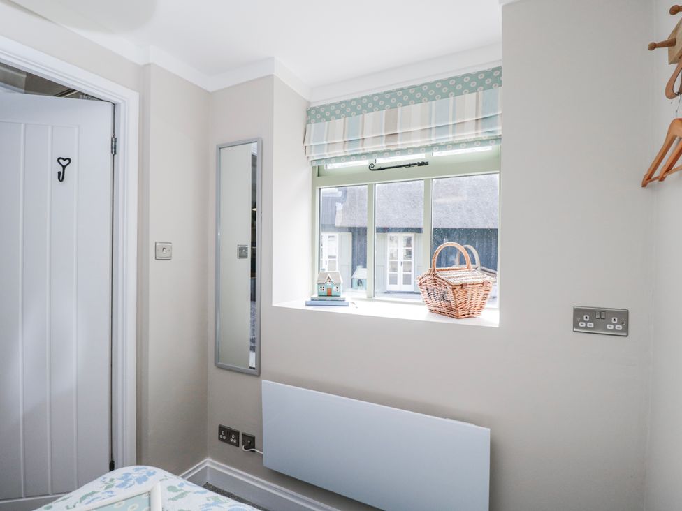 A bedroom with a window and a mirror at Firefly Cottage