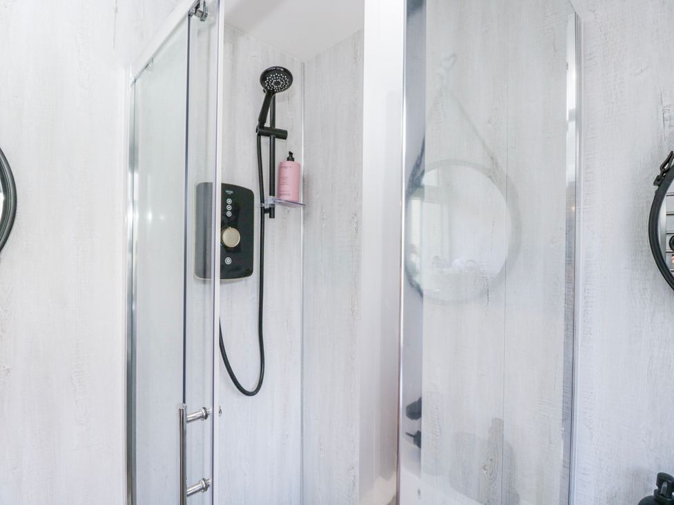 A shower with glass doors and fixtures in Firefly Cottage