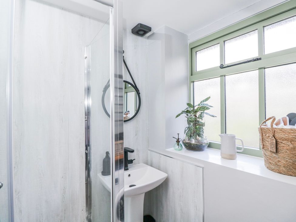 A bathroom with a shower, sink, and window at Firefly Cottage