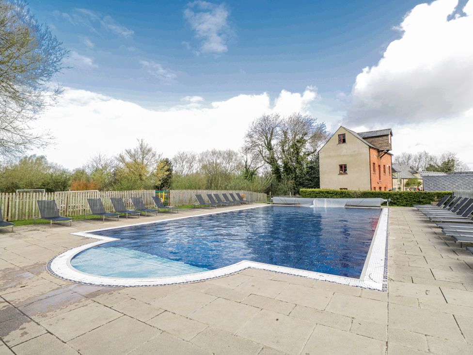 An outdoor swimming pool surrounded by lounge chairs at Firefly Cottage