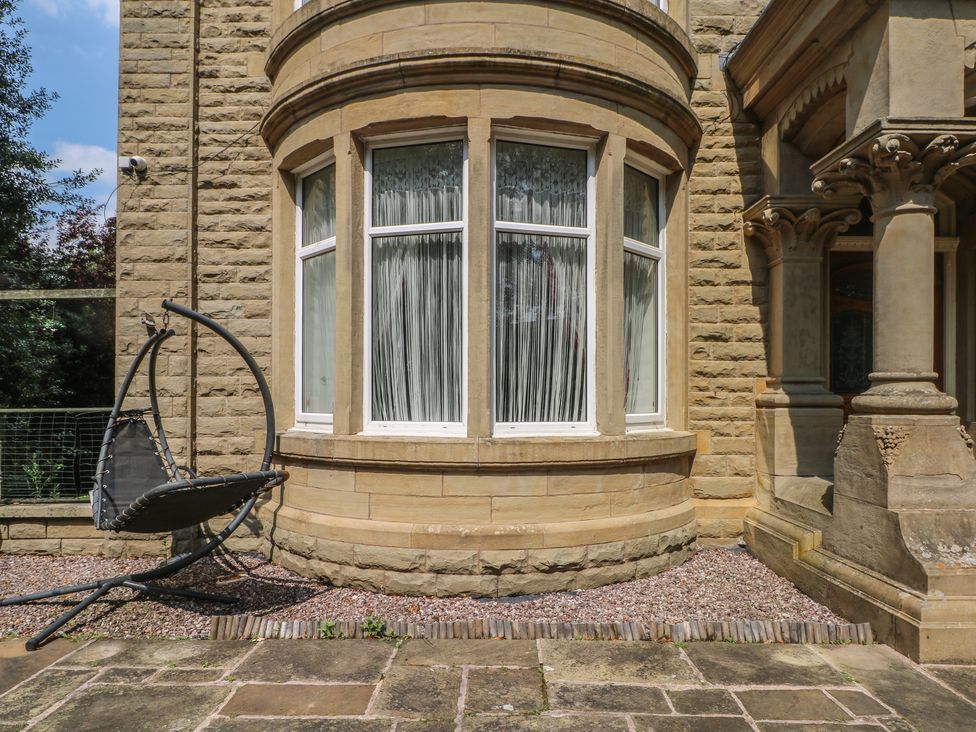 An outdoor area with a window and hanging chair at Stone House in Rossendale