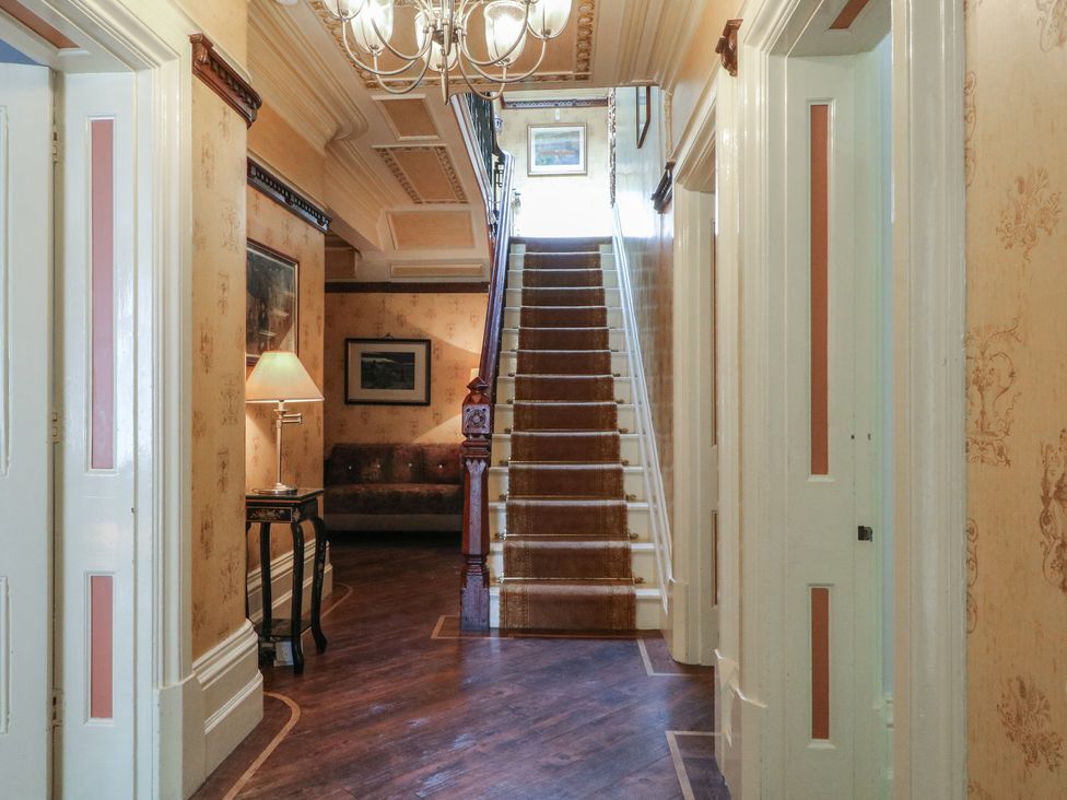 A hallway with a staircase and lamp at Stone House in Rossendale