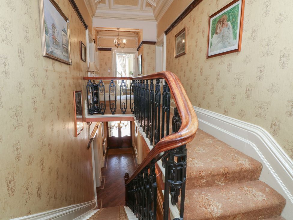 A staircase with a wooden handrail and wall art at Stone House in Rossendale