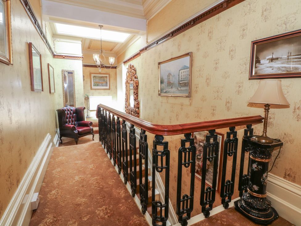 A hallway with a staircase and armchair at Stone House in Rossendale