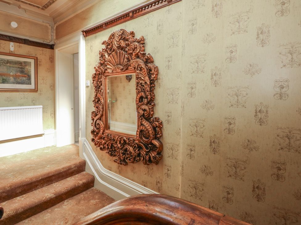 A hallway with a mirror, painting, and radiator at Stone House in Rossendale