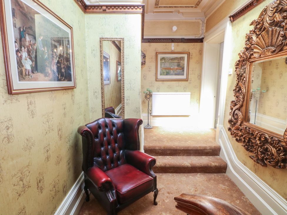 A hallway with a chair and mirrors at Stone House in Rossendale