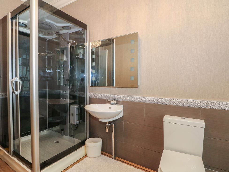 A bathroom with a shower, washbasin, and toilet at Stone House in Rossendale