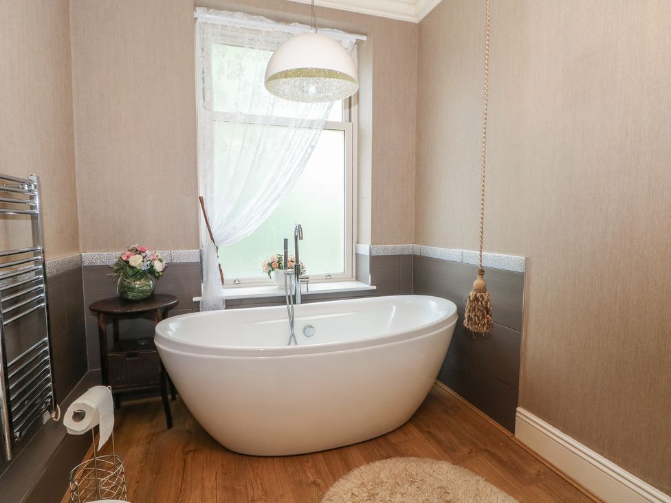 A bathroom with a bathtub and a towel rack at Stone House in Rossendale