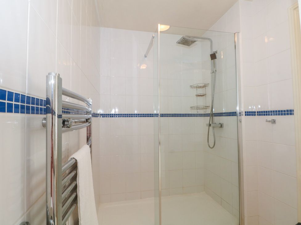 A bathroom with a shower and towel rail at Stone House in Rossendale