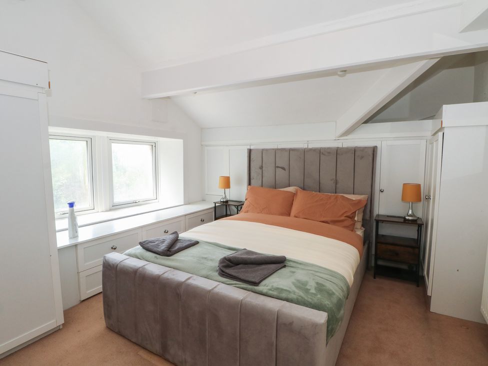 A bedroom with a bed and two windows at Stone House in Rossendale