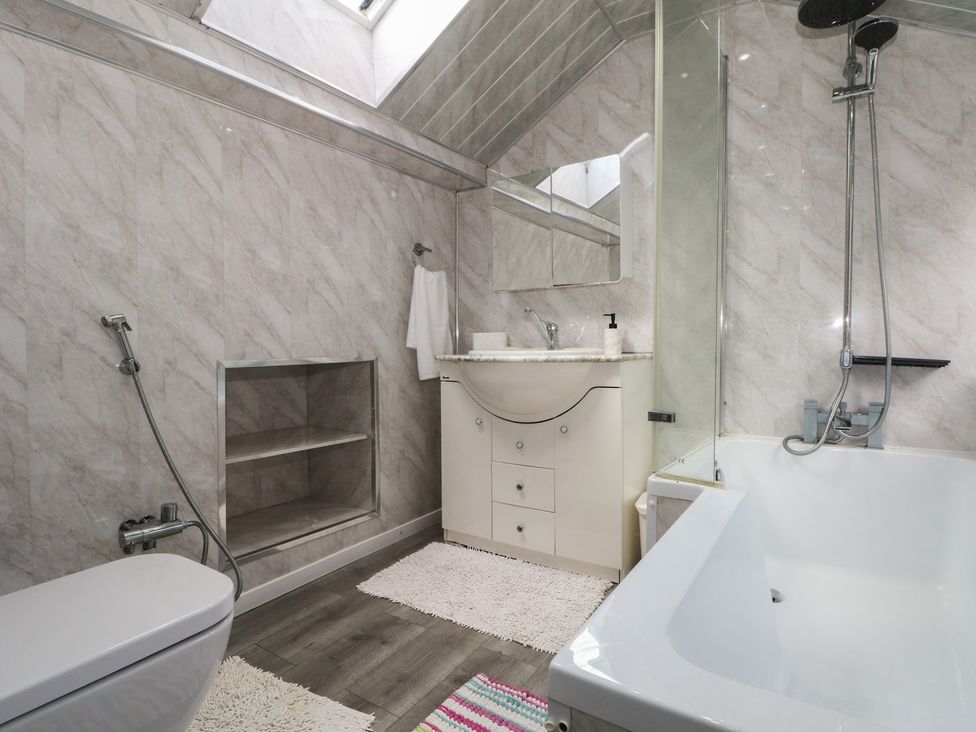 A bathroom with a bathtub, sink, and shower at Stone House in Rossendale