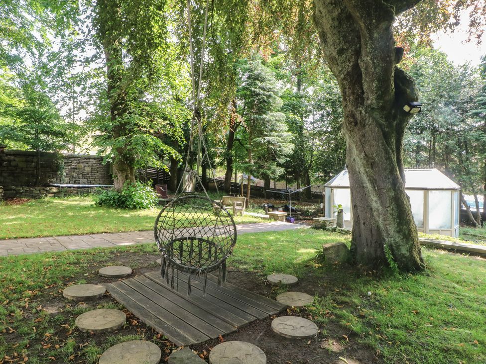 A garden with a hanging chair and stone pathway at Stone House in Rossendale