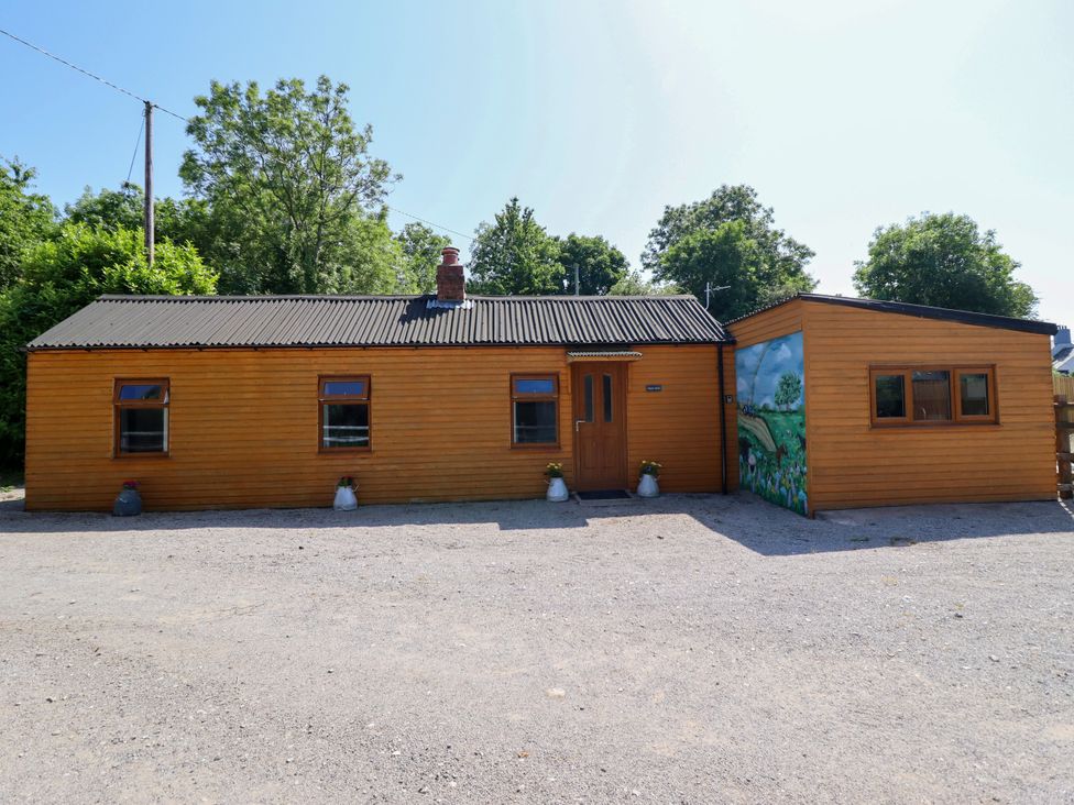 A wooden house with a mural and a gravel area at Haven in Lloc near Holywell